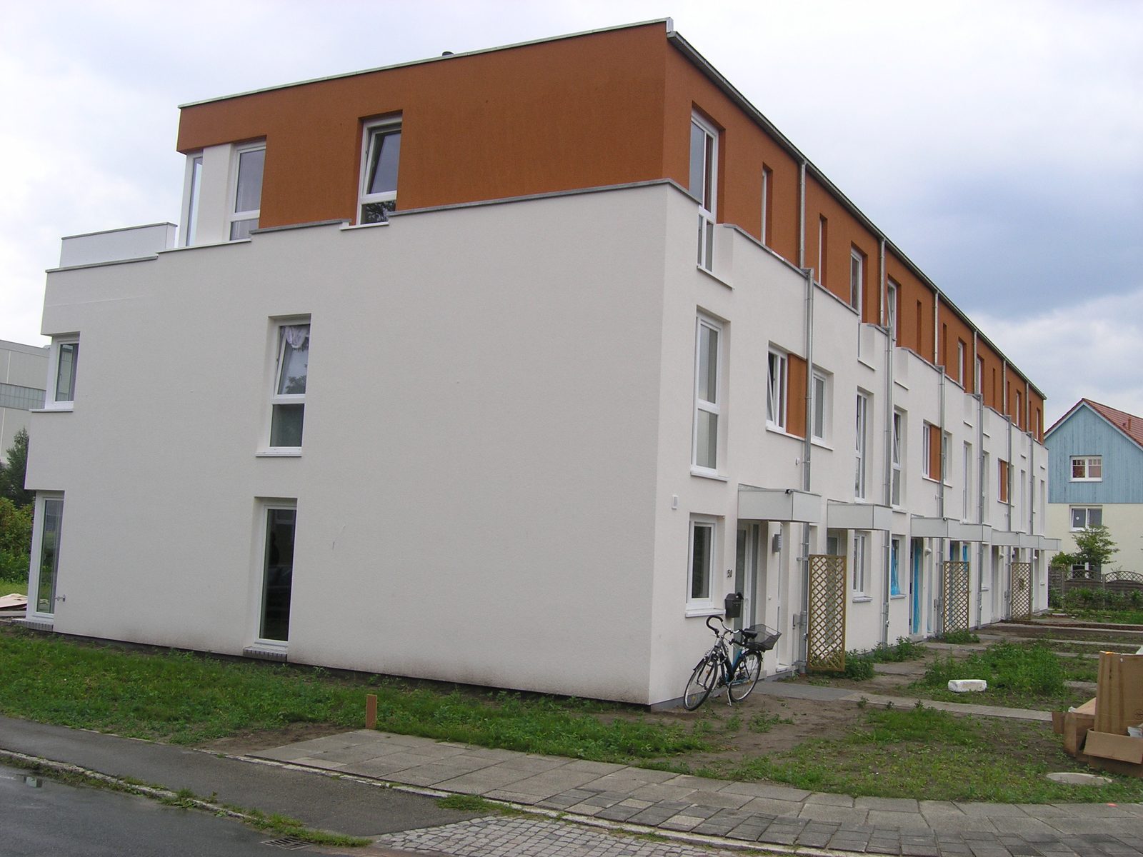 Kopfbau der Zeile mit dem orange abgesetzten Staffelgeschoss