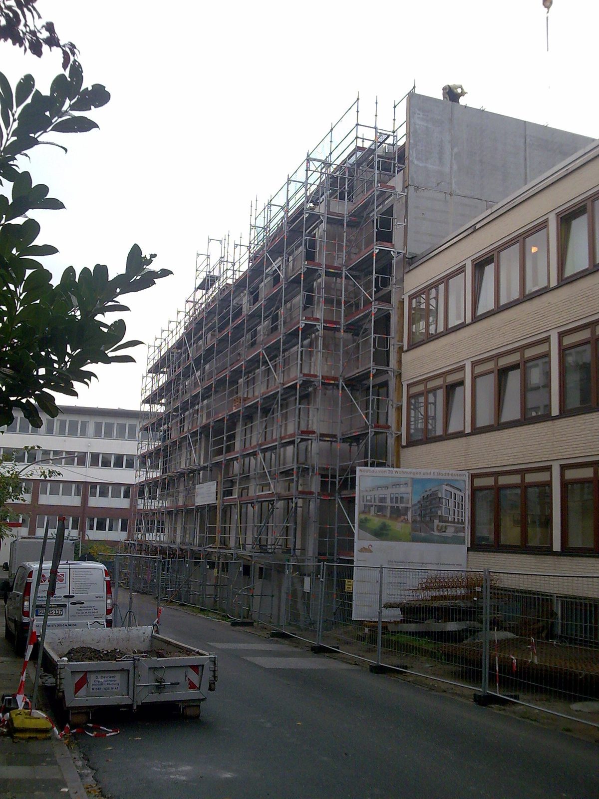 Das eingerüstete Gebäude mit dem Bauschild an der Straße